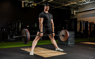 An athlete deadlifting with Rep Fitness Calibrated Steel Plates (KG) loaded on the barbell