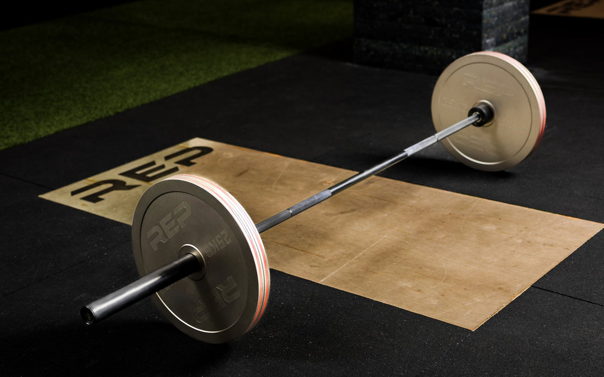 Athlete loading Rep Fitness Calibrated Steel Plates (KG) onto a barbell using the REP® x Kleva Built® Genesis Jack® 2.0